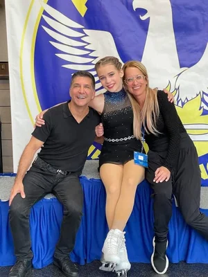 Tracey rinkside at a figure skating competition with a young skater and another coach.