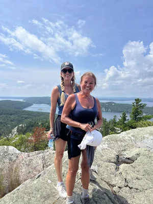 Tracey at the summit of a hiking trail overlooking a lake.