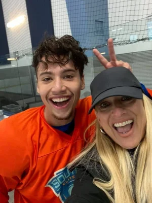 Tracey at a hockey rink with a player in an orange jersey.