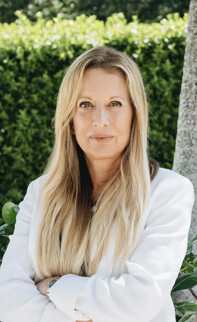 Tracey Potter, arms crossed, standing in front of a hedge in natural light.