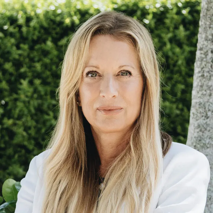 Tracey Potter, arms crossed, standing in front of a hedge in natural light.