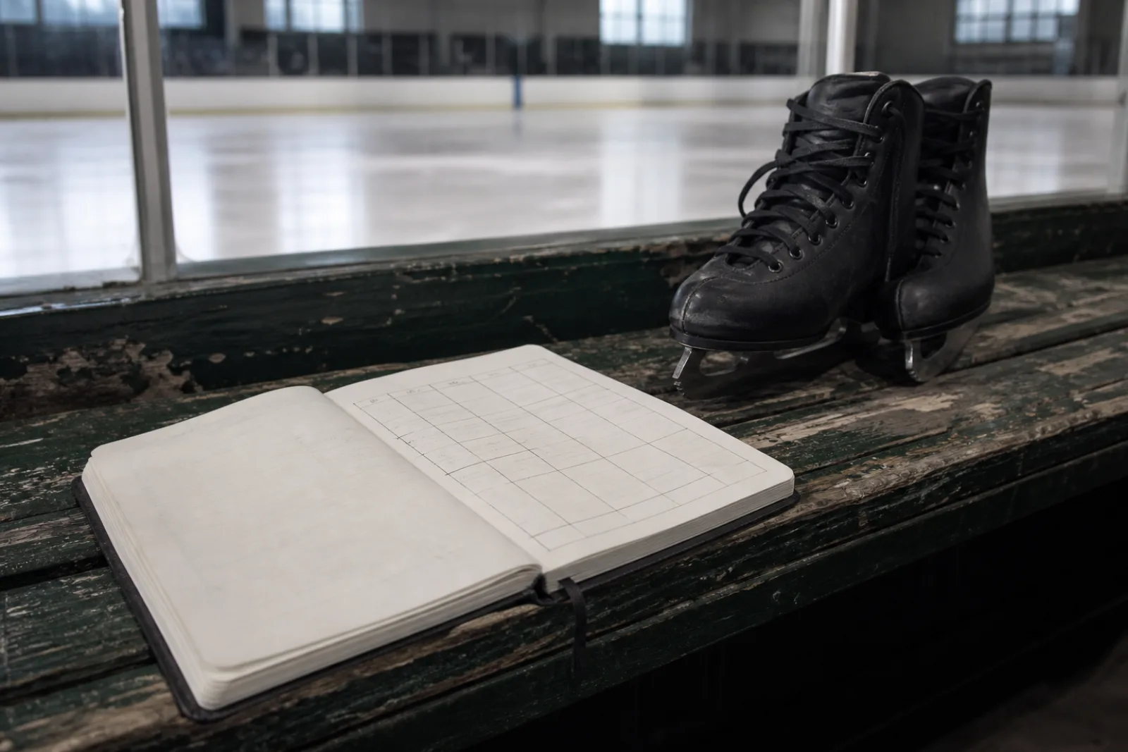 A planning notebook and figure skates on a rink bench